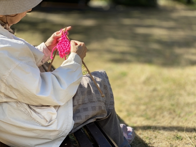 公園で指編みする高齢者
