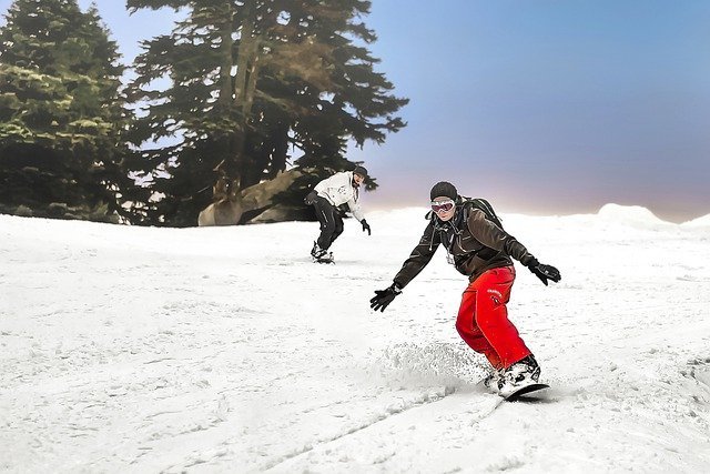 スノーボードをする赤いズボンの男性