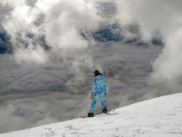 青いスキーウェアでスノボをする人
