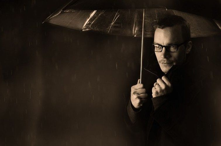 傘をさしたメガネの男性