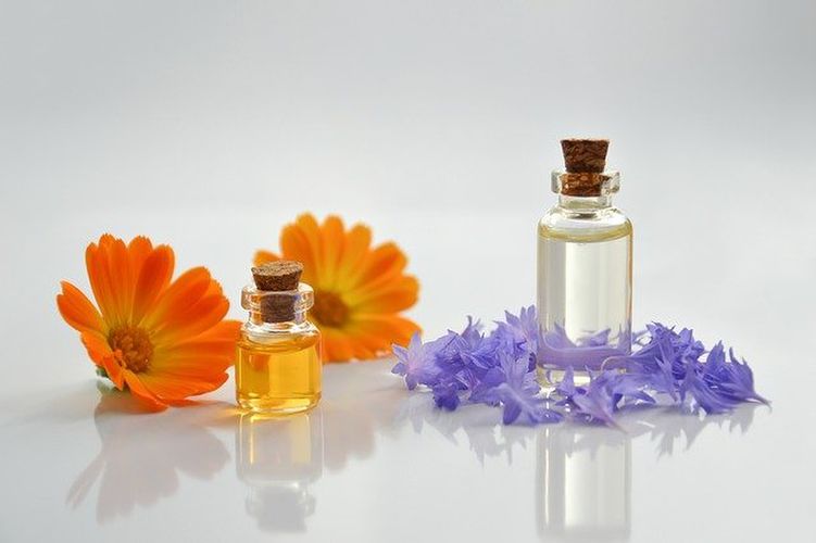オレンジや紫の花と並ぶオイルの小瓶